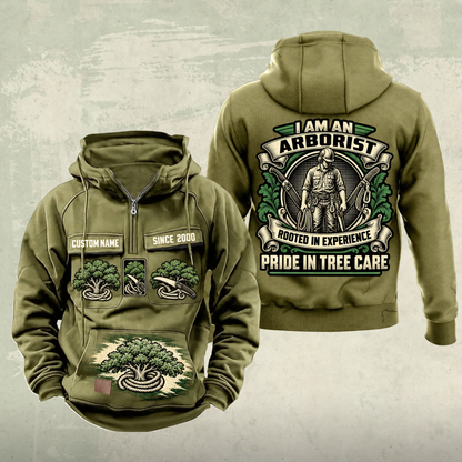 Arborist Heritage Crest Vintage Hoodie in Military Green, front and back views with sample chest text CUSTOM NAME and SINCE 2000, ornate arborist back crest, tree-and-rope chest graphics and lower brush-stroke motif.
