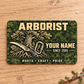 Front of the Arborist Rugged Field aluminum wallet card on pale oak.