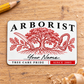 Front of the Arborist Signature Classic aluminum wallet card on pale wood.