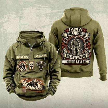Bull Rider Heritage Crest Vintage Hoodie in Military Green, front and back views with ornate cowboy-and-rope crest, chest and lower-panel bull motifs, plain sleeves, and sample text CUSTOM NAME and SINCE 2000.