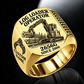 John Deere 2656G Log Loader Operator Ring in Gold finish, flat engraving showing plain two-jaw log grapple on a loading boom, CUSTOM NAME and SINCE 2000.