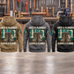 Plumber Once and Always Vintage Hoodies in Military Green, Kaki, Dark Gray, Black and Dark Blue, showing five complete separated back views with teal-and-cream boots and pipework artwork in an organized plumbing workshop.