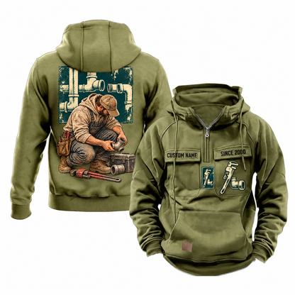 Plumber Ready Every Day Portrait Vintage Hoodie in Military Green, front and back views with sample text CUSTOM NAME and SINCE 2000, chest tool emblems and kneeling plumber back artwork.