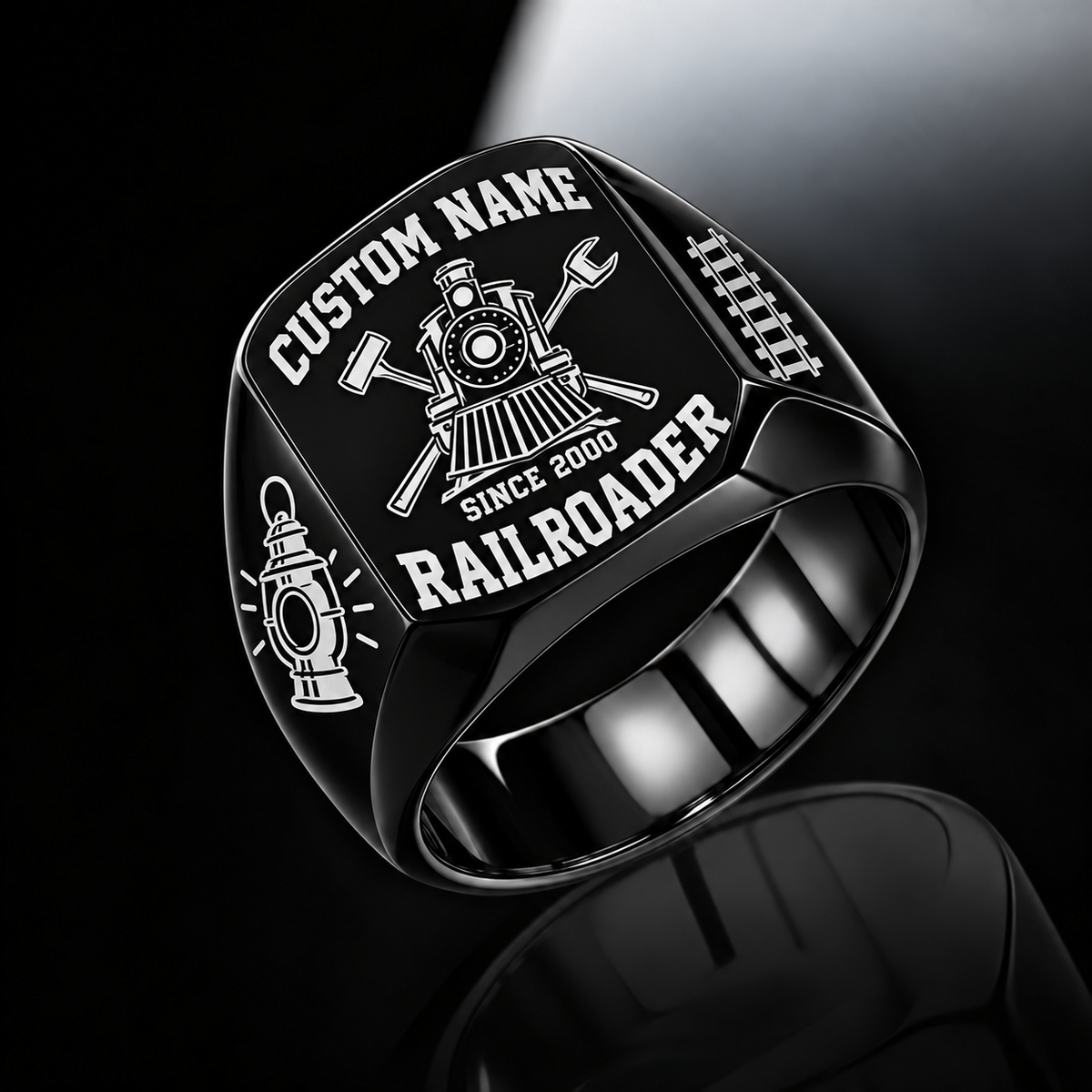 Black Railroader Bold Lettering ring with a front-facing locomotive over crossed railway-tool silhouettes, framed by bold name and profession lettering, with railway lantern and track shoulder motifs, with illustrative CUSTOM NAME and SINCE 2000 artwork
