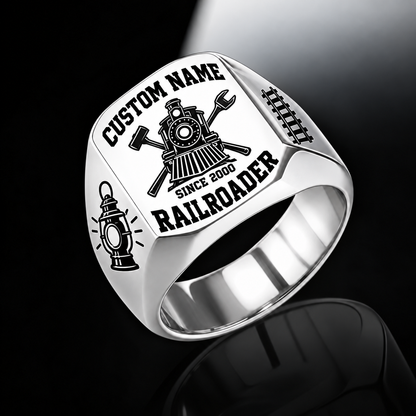 Silver Railroader Bold Lettering ring with a front-facing locomotive over crossed railway-tool silhouettes, framed by bold name and profession lettering, with railway lantern and track shoulder motifs, with illustrative CUSTOM NAME and SINCE 2000 artwork