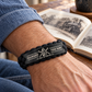 Railroader black braided bracelet worn on a relaxed adult wrist at home beside a railway history book