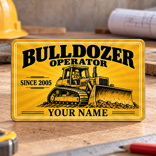 Front of the Bulldozer Operator Golden Milestone aluminum wallet card, with a tracked bulldozer, golden sunburst, and illustrative SINCE 2005 and YOUR NAME text, upright on a planning desk.