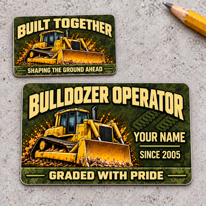 Front and reverse of the Bulldozer Operator Rugged Field aluminum wallet card, offset on pale concrete, with olive pixel camouflage, tan lettering and a yellow tracked bulldozer with front blade.