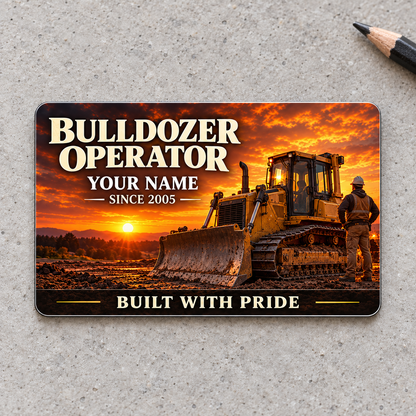 Front of the Bulldozer Operator Sunset Workday aluminum wallet card, with cream serif lettering, a tracked bulldozer and broad front blade against an amber sunset on warm gray concrete.