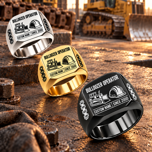 Black-led diagonal arrangement of Bulldozer Operator Twin Icons signet rings in Silver, Gold and Black on a heavy-equipment workbench, with tracked bulldozer and hard-hat symbols and sample CUSTOM NAME and SINCE 2000 engraving.