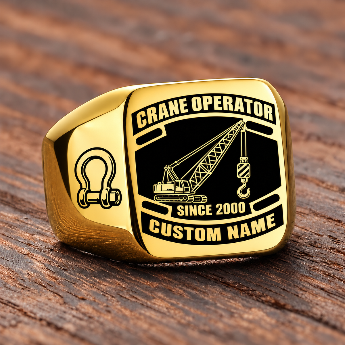 Gold-finish Crane Operator Black Face Badge ring with lattice crane, suspended hoist hook, shoulder shackle and illustrated CUSTOM NAME and SINCE 2000 text