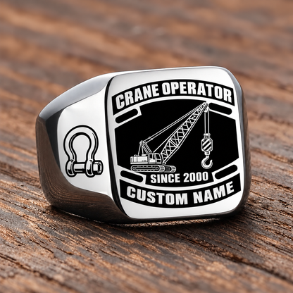 Silver-finish Crane Operator Black Face Badge ring with lattice crane, suspended hoist hook, shoulder shackle and illustrated CUSTOM NAME and SINCE 2000 text