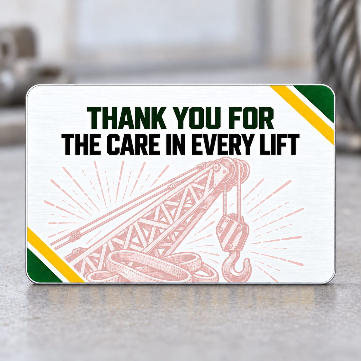 Reverse of the Crane Operator Green Band aluminum wallet card with Thank You for the Care in Every Lift lettering, a pale pink crane-and-rigging illustration, and green-and-yellow diagonal corner accents.
