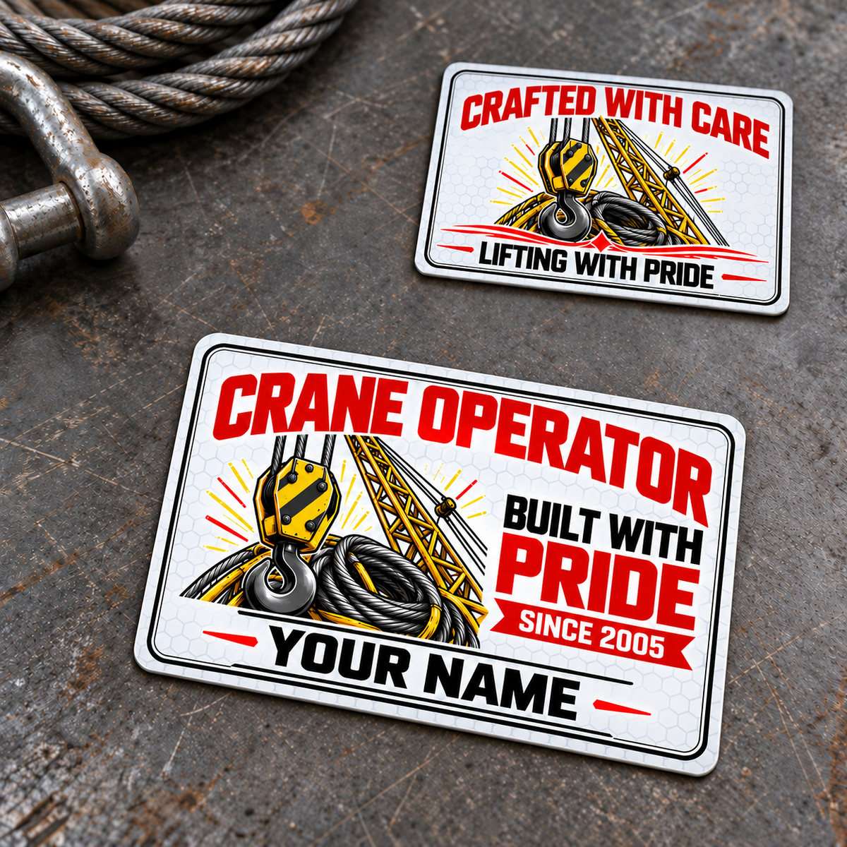 Front and reverse of the Crane Operator Honeycomb Pride aluminum wallet card on a stationary rigging workbench, with yellow crane hook and lattice-boom artwork, white honeycomb, black double borders, red trade-pride lettering and illustrative YOUR NAME and SINCE 2005 text.