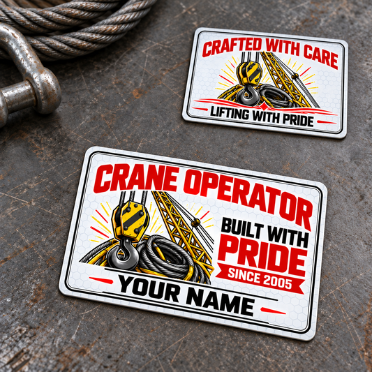 Front and reverse of the Crane Operator Honeycomb Pride aluminum wallet card on a stationary rigging workbench, with yellow crane hook and lattice-boom artwork, white honeycomb, black double borders, red trade-pride lettering and illustrative YOUR NAME and SINCE 2005 text.