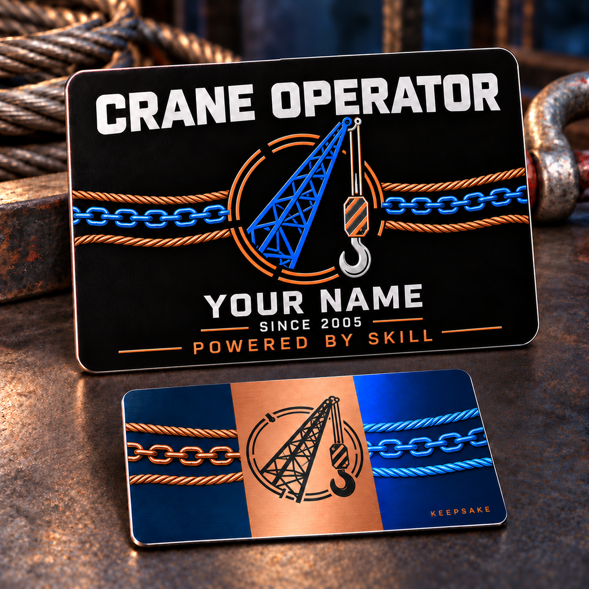 Front and reverse of one Crane Operator Midnight Copper Stripe aluminum wallet card on a stationary rigging workbench, with blue crane boom and suspended hook, copper twisted rope and connected blue chain on the black front, illustrative YOUR NAME text, and a navy-blue reverse with a copper center stripe, black crane emblem and matching connected rigging artwork.