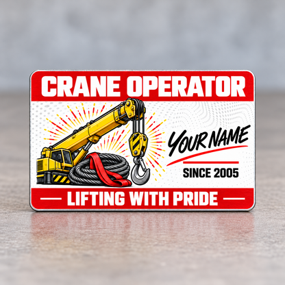 Front of the Crane Operator Red Header aluminum wallet card standing upright on a pale gray tabletop, with red header and footer bands, yellow crane boom and hook, gray wire rope, red sling, and illustrative name and year.