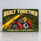 Reverse of the Crane Operator Rugged Field aluminum wallet card, with Built Together and Raising Ideas to New Heights lettering, yellow crane boom, hanging hook, gray wire rope and red lifting sling over olive pixel camouflage.