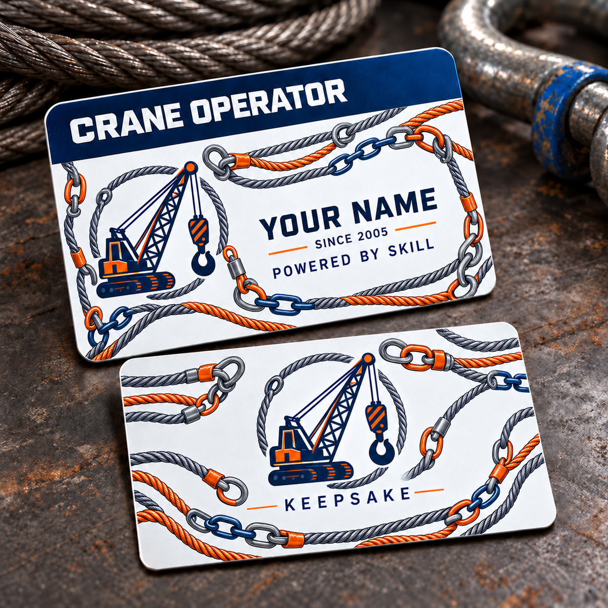 Front and reverse views of one Crane Operator Signature Stripe aluminum wallet card on a stationary rigging tabletop, with a navy occupation stripe, crane boom and hook emblems, twisted steel rope and connected navy and copper-orange rigging links, illustrative Your Name text, Powered by Skill and Keepsake.