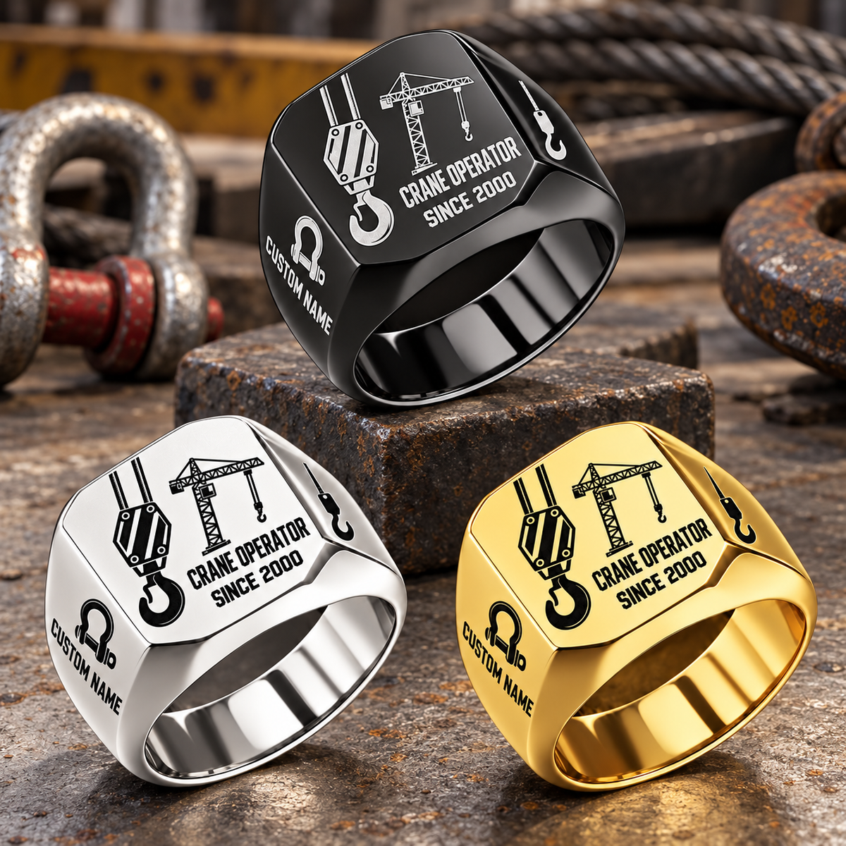 Crane Operator Split Emblem signet rings in a Black-led triangular arrangement, with Silver and Gold finishes on a staged crane-rigging workbench