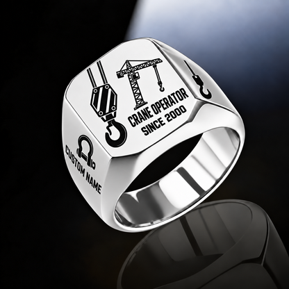 Silver-finish Crane Operator Split Emblem signet ring with split-face hoist hook and tower crane, plus bow-shackle and hook shoulder motifs and illustrated CUSTOM NAME and SINCE 2000 text