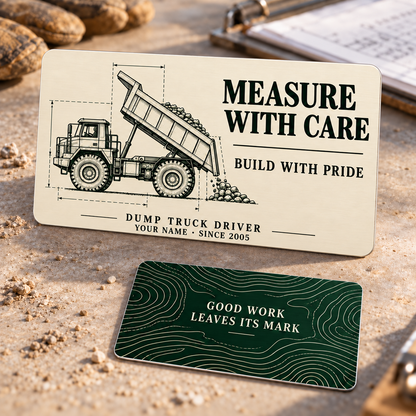 Measure with Care dump truck driver aluminum wallet card showing ivory front and forest-green reverse with technical dump truck and quarry contour artwork.