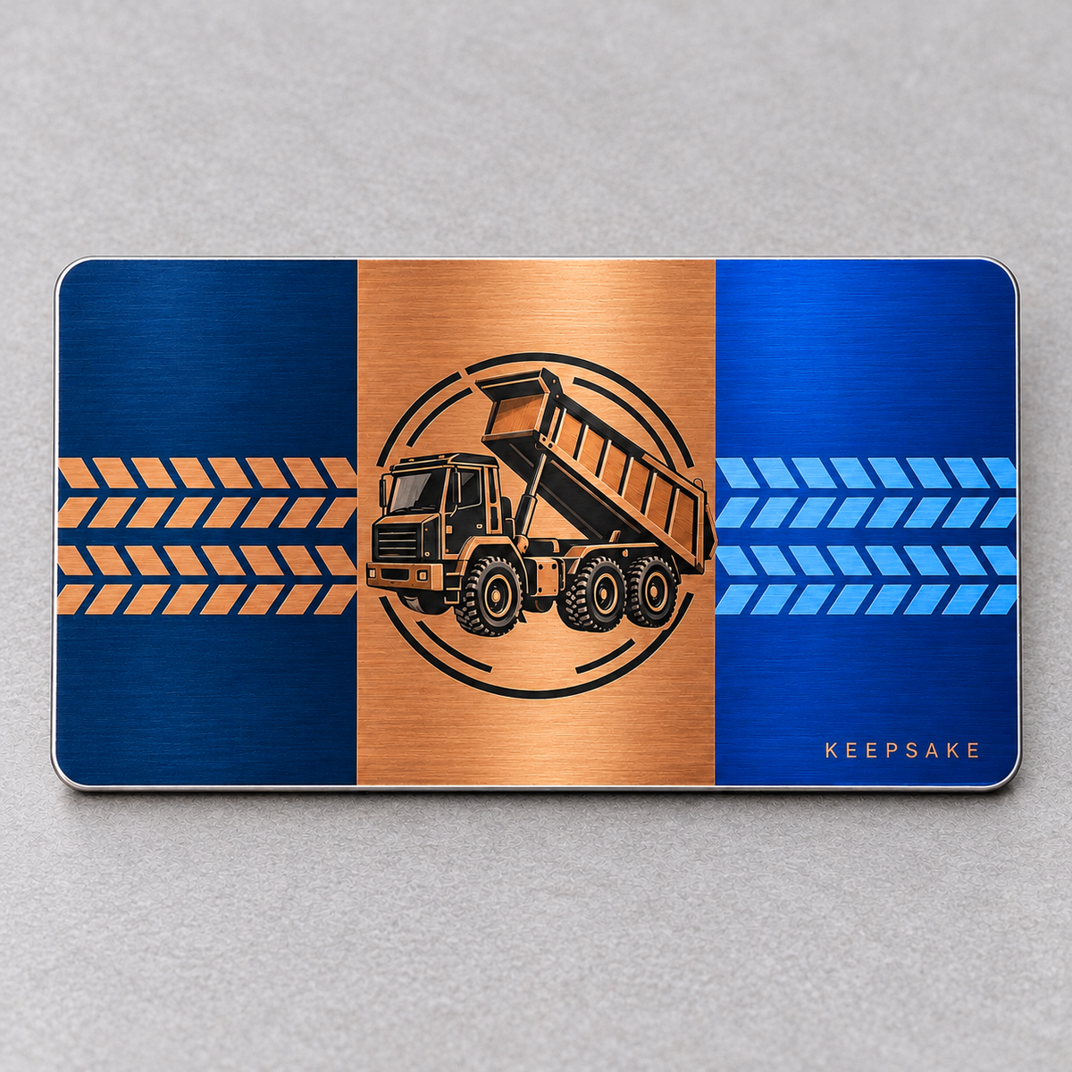 Reverse of the Dump Truck Driver Midnight Pride aluminum wallet card, showing navy, copper and blue panels with dump truck, tire treads and Keepsake lettering.