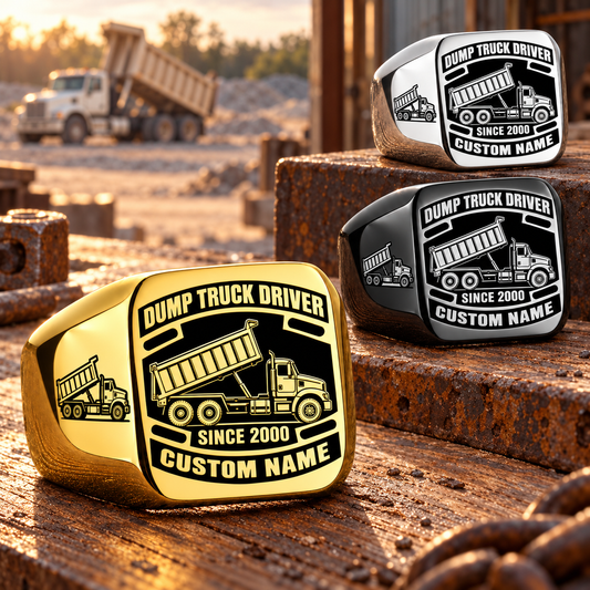 Dump Truck Driver Black Face Badge rings in a Gold-dominant diagonal arrangement with Black and Silver finishes on a stationary workshop table; illustrated CUSTOM NAME and SINCE 2000 text