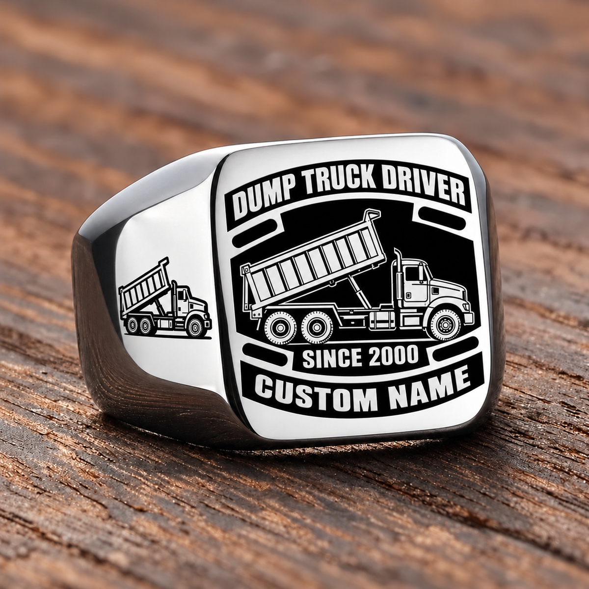 Silver-finish Dump Truck Driver Black Face Badge ring with high-sided tipping-bed truck artwork, matching shoulder truck, and illustrated CUSTOM NAME and SINCE 2000 text