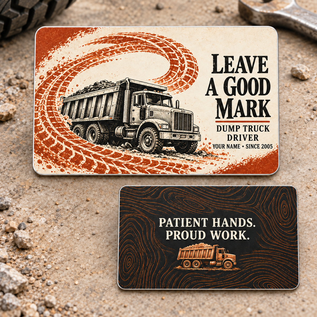 Both sides of the Dump Truck Driver Leave a Good Mark aluminum wallet card: an ivory front with orange tire track and black dump truck, and a black reverse reading Patient Hands. Proud Work.