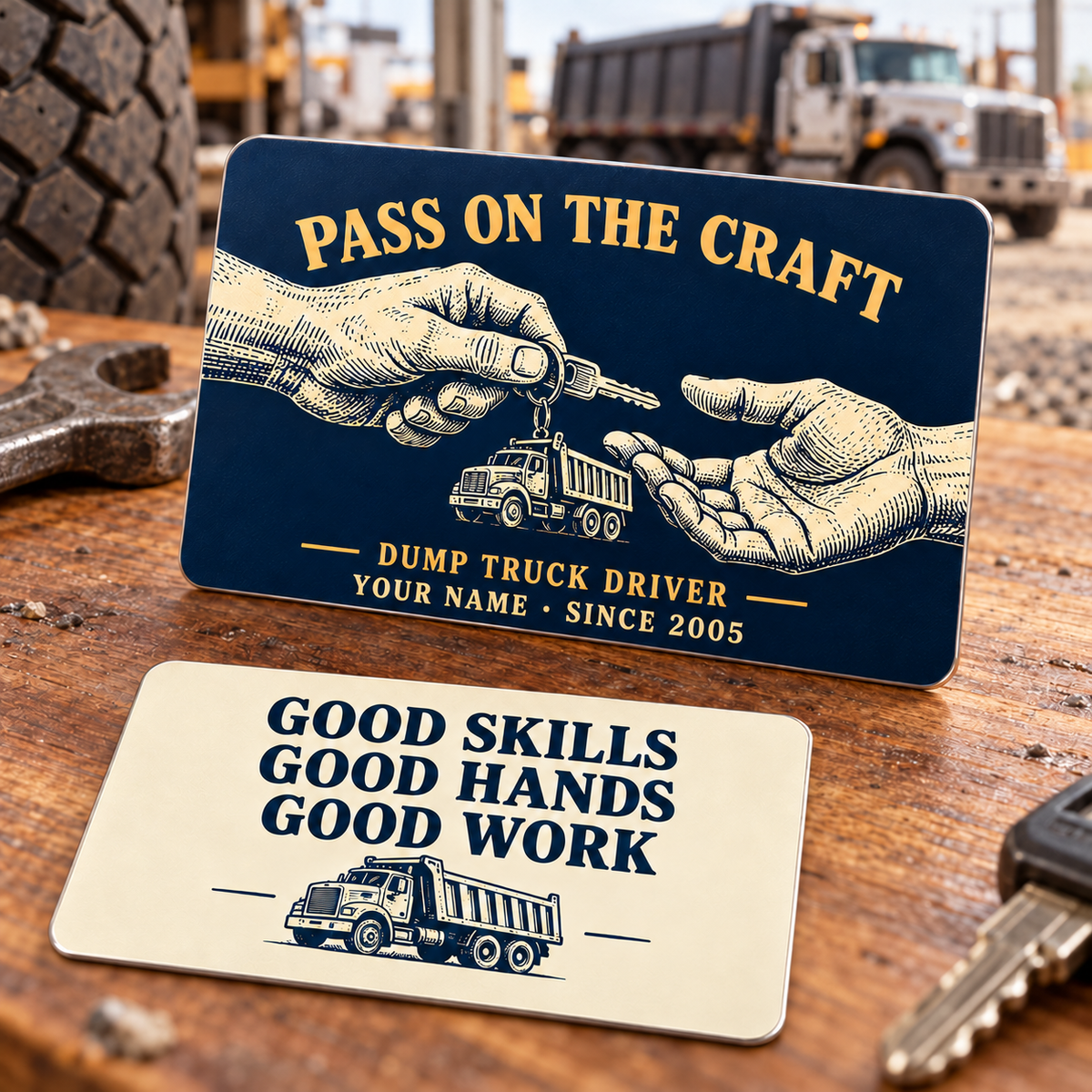 Front and reverse of the Dump Truck Driver Pass on the Craft aluminum wallet card, with navy and gold artwork of hands passing a truck key and a cream reverse reading Good Skills, Good Hands, Good Work.