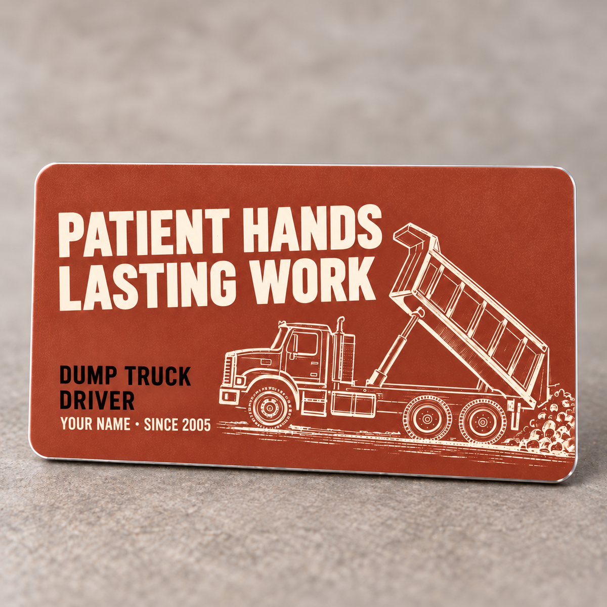 Terracotta front of the Dump Truck Driver Patient Hands aluminum wallet card with cream raised-bed dump truck artwork and black occupation text.