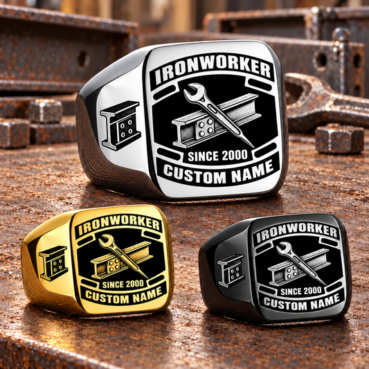 Ironworker Black Face Badge rings in Silver, Gold and Black, with a dominant Silver ring above two smaller finishes on a stationary structural-steel tabletop; sample CUSTOM NAME and SINCE 2000 text