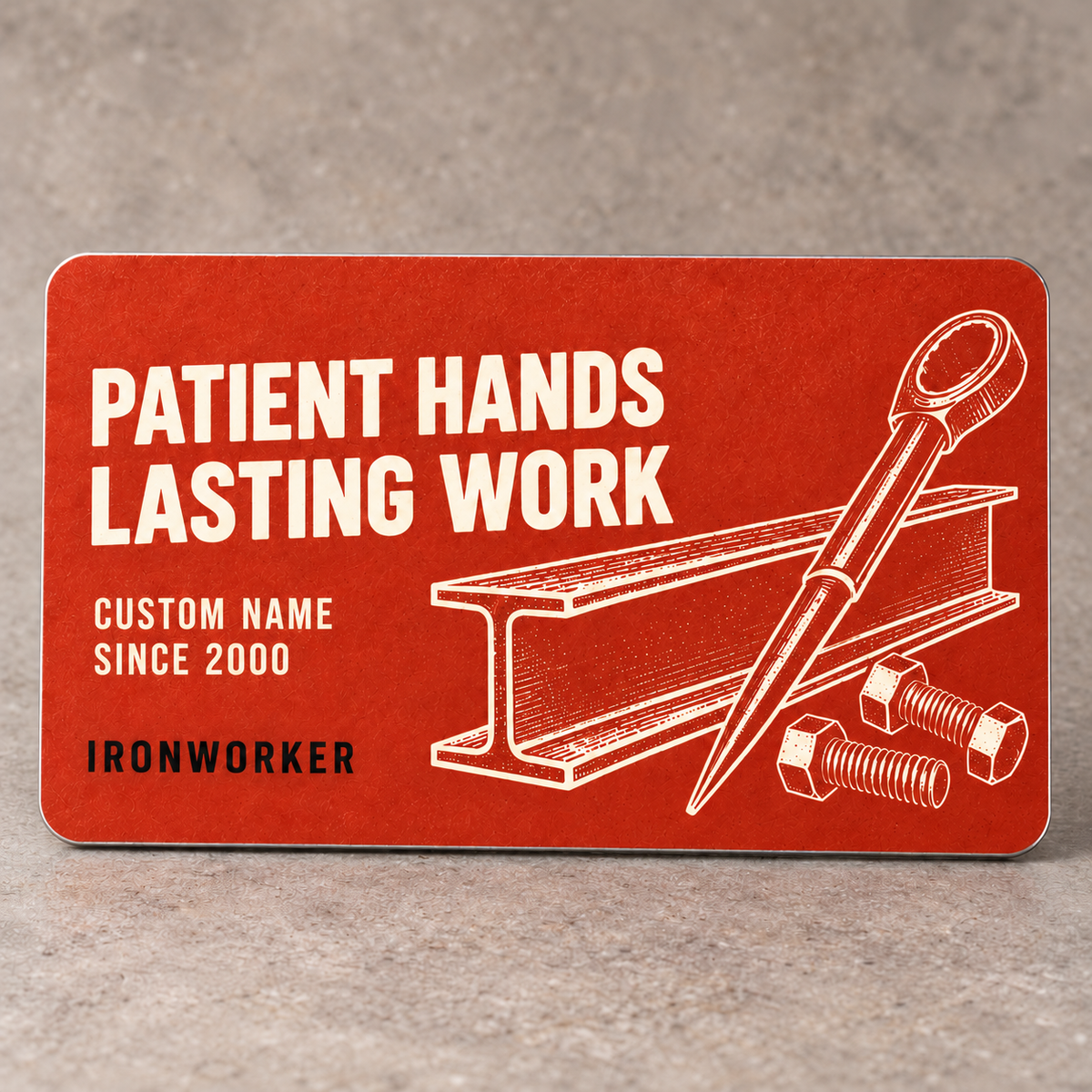 Terracotta front of the Ironworker Patient Hands aluminum wallet card with cream steel I-beam, tapered spud wrench and bolt artwork.