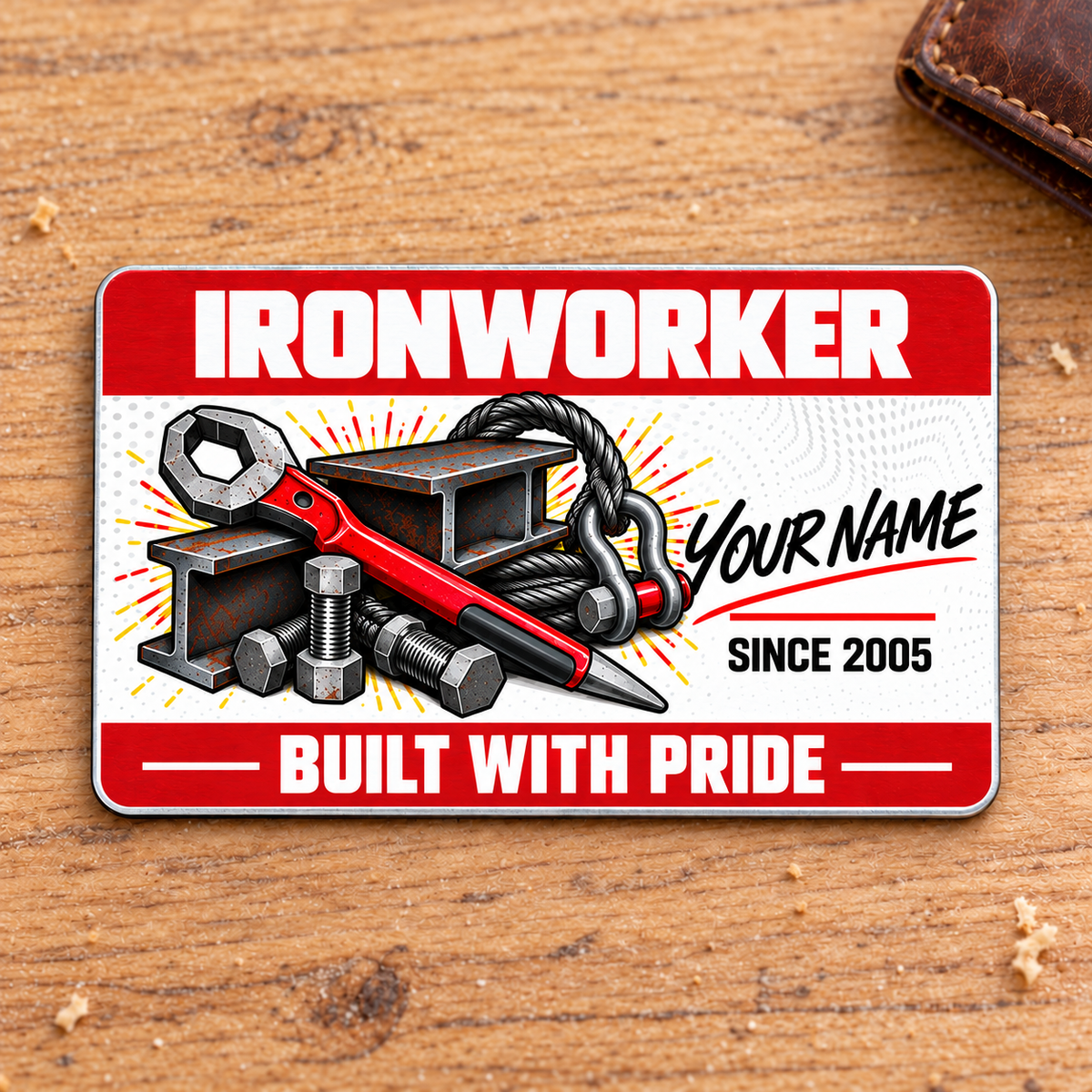 Ironworker Red Header aluminum wallet card front on warm oak with bold white lettering, a dotted-wave center, red spud wrench, I-beams, structural bolts and a lifting sling.