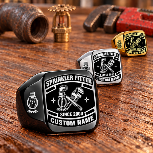 Sprinkler Fitter Black Face Badge rings in a Black-led receding row with Silver and Gold finishes on a stationary fire-sprinkler fitting workbench