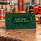 Dark forest-green reverse of the Sprinkler Fitter aluminum wallet card with fine ivory woodgrain print and Good Work Leaves Its Mark. Styling props are not included.