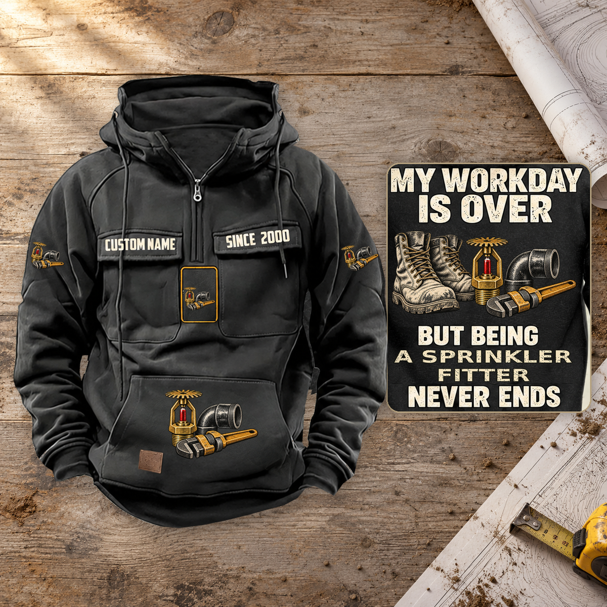 Sprinkler Fitter Never Ends Vintage Hoodie in Black on a warm planning workbench, dominant front view with a complete rear-art detail inset.