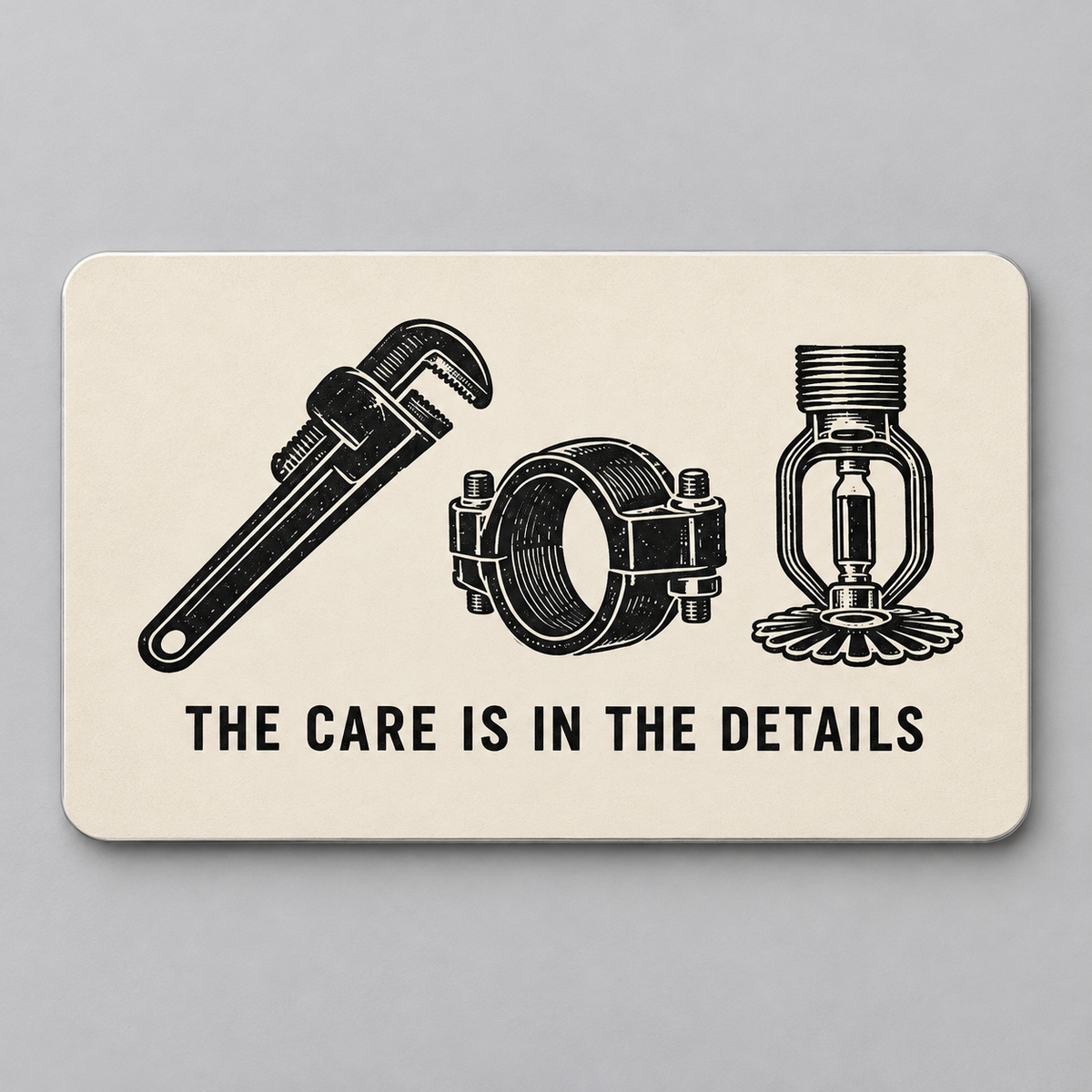 Cream reverse of the Sprinkler Fitter aluminum wallet card with a black pipe wrench, coupling and fire-sprinkler head above The Care Is in the Details.