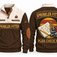 Sprinkler Fitter Plan Check Fit Sports Sweatshirt in Brown, original front and back views. A fire sprinkler head, steel pipe fittings and a pipe wrench over a plan sheet and pencil within a distressed sunset roundel. SPRINKLER FITTER and PLAN CHECK FIT lettering; YOUR NAME and SINCE 2000 are fixed illustrative sample text.