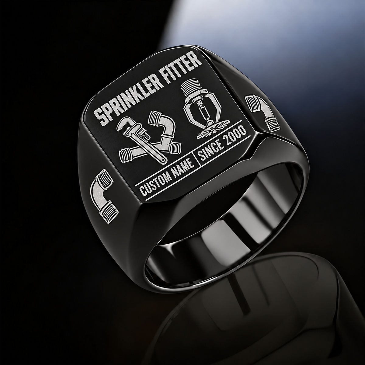 Black-finish Sprinkler Fitter Twin Icons signet ring with pipe wrench and connected fittings beside a pendent fire sprinkler, elbow shoulder emblems and illustrated CUSTOM NAME and SINCE 2000 text