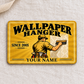 Wallpaper Hanger Golden Milestone aluminum wallet card front on cream linen, showing a worker smoothing wallpaper and illustrative SINCE 2005 and YOUR NAME text.