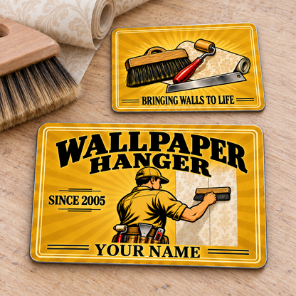 Front and reverse of the Wallpaper Hanger Golden Milestone aluminum wallet card on a wallpaper worktable, with golden sunburst artwork and illustrative name and year text.