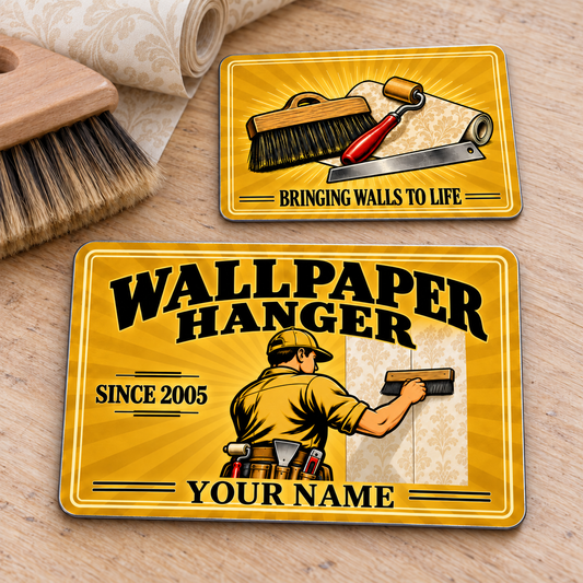 Front and reverse of the Wallpaper Hanger Golden Milestone aluminum wallet card on a wallpaper worktable, with golden sunburst artwork and illustrative name and year text.