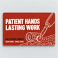 Brick-red front of the Wallpaper Hanger Patient Hands aluminum wallet card, with Patient Hands, Lasting Work lettering and wallpaper roll and seam roller line art.