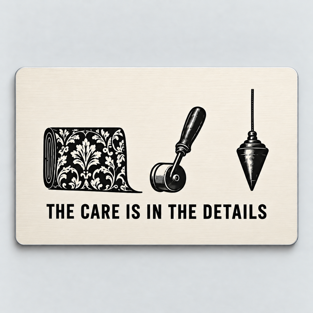 Ivory reverse of the Wallpaper Hanger Patient Hands aluminum wallet card, showing a wallpaper roll, seam roller and plumb bob above The Care Is in the Details.