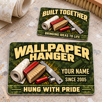 Front and reverse of one Wallpaper Hanger Rugged Field aluminum wallet card with olive camouflage, tan lettering and wallpapering tools on a pale workbench.