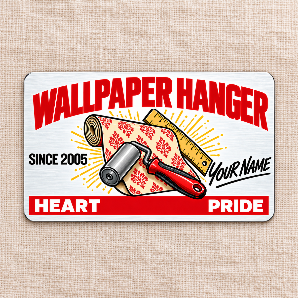 Front of the Wallpaper Hanger Signature Classic aluminum wallet card on linen, with red heading, patterned wallpaper roll, seam roller and ruler, and illustrative name and year text.