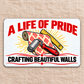 Reverse of the Wallpaper Hanger Signature Classic aluminum wallet card, with wallpaper tools, red ornamental swashes, A LIFE OF PRIDE and CRAFTING BEAUTIFUL WALLS lettering.
