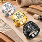 Wallpaper Hanger Signature Crest rings in a Black-led diagonal arrangement with Silver and Gold finishes on a stationary wallpaper tools and swatches table